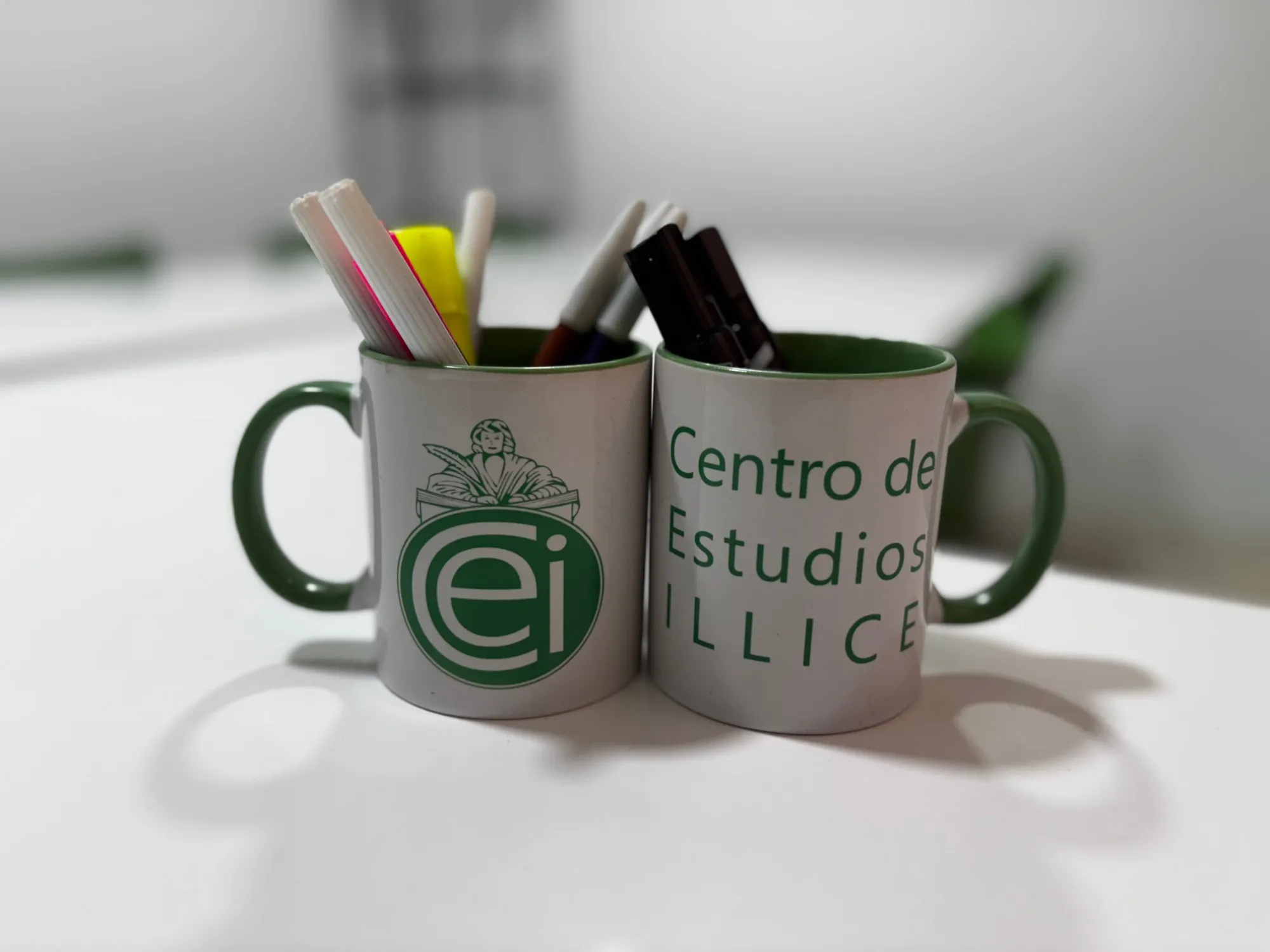 Tazas con el logo del Centro de Estudios Illice llenas de rotuladores